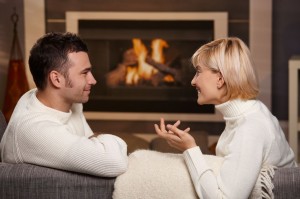 002944219_Young-romantic-couple-sitting-on-sofa-in-front-of-fireplace-at-home-looking-at--300x199